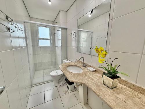 Un baño con lavabo, inodoro y ducha. en Edifício Baalbek, en Mongaguá