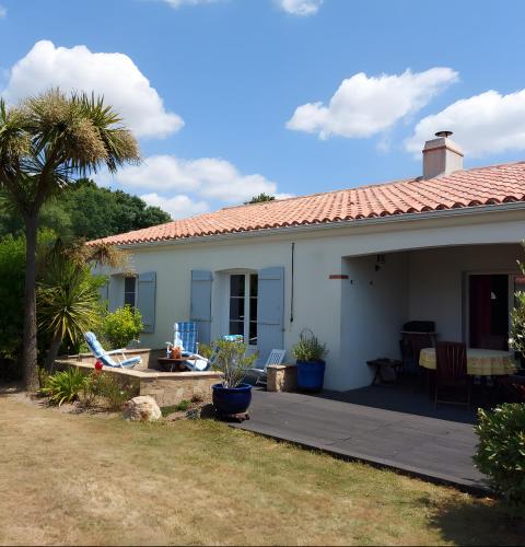 une maison blanche avec une terrasse et un palmier dans l'établissement 01 - Pornicaise aux volets bleus, à Pornic