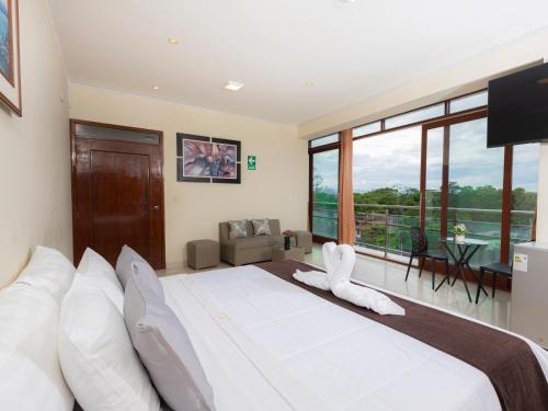 a bedroom with a large white bed with a large window at Hotel San Marino Tarapoto in Tarapoto