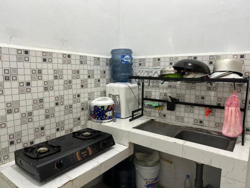 a kitchen with a sink and a stove in it at Alceo Homestay in Halangan