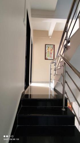 a staircase with black steps and a picture on the wall at Aayushi Homestay Ratnagiri in Math