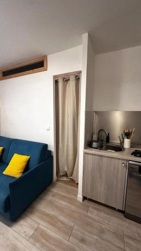 un salon avec un canapé bleu et une cuisine dans l'établissement Appartement 2 pieces centre Menton jardin Bioves, à Menton