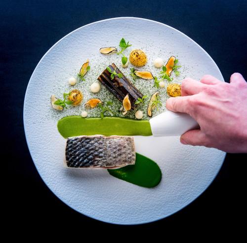 a plate of food with a person holding a knife at Domaine de Clairefontaine - Teritoria in Chonas-lʼAmballan