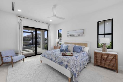 a bedroom with a bed and a chair and windows at Exquisite waterfront Home featuring a pool and hot tub in Marco Island