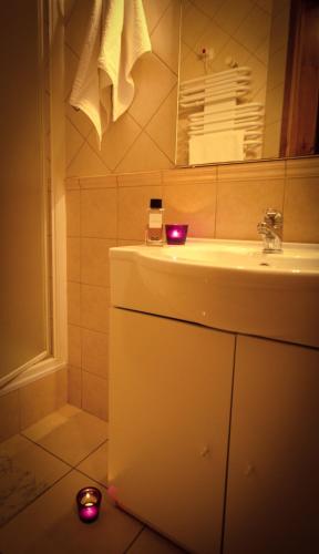 ein Badezimmer mit einem Waschbecken und zwei Kerzen auf dem Boden in der Unterkunft Kemencés Csárda és Panzió in Hajdúszoboszló