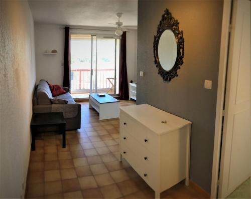 un salon avec un canapé et un miroir dans l'établissement Les Sablettes studio et sa loggia vue mer, à La Seyne-sur-Mer