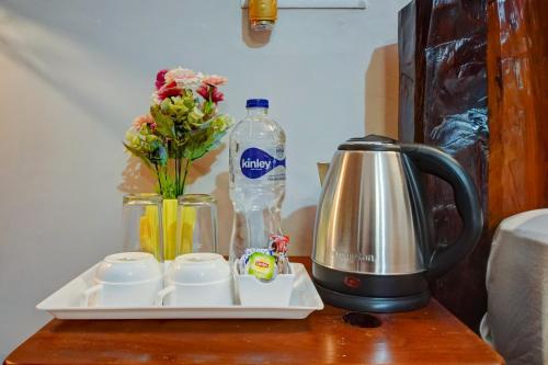 a coffee maker on a table with flowers and a bottle of water at Nature's Vibe Stays Mukteshwar - A 4BHK Plum Orchard Villa in Mukteswar