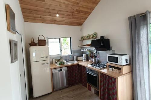 Il comprend une cuisine équipée d'un réfrigérateur blanc et d'une cuisinière. dans l'établissement Restored barn in its Landes airial, à Léon