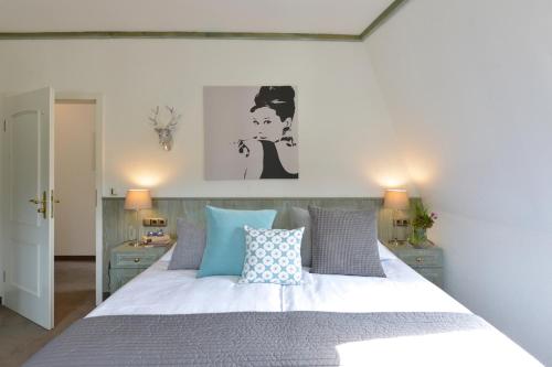 a bedroom with a large white bed with blue pillows at Sommers Hotel Altes Posteck in Reichenbach im Vogtland