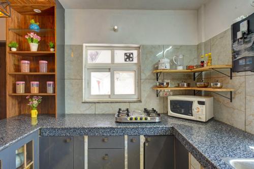 a kitchen with a counter top and a microwave at Nature's Vibe Stays Mukteshwar - A 4BHK Plum Orchard Villa in Mukteswar