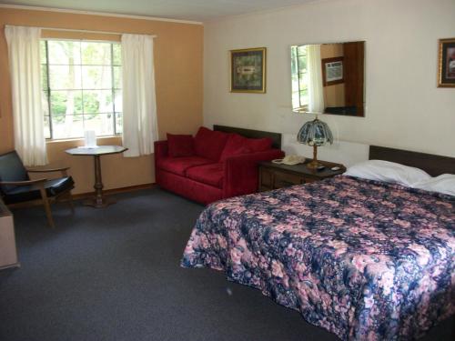 Habitación de hotel con cama y sofá rojo en Two Rivers Lodge, en Bryson City