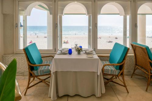 a dining room with a table and chairs and the beach at Hotel Playa Victoria in Cádiz