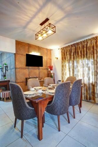 a dining room with a table and chairs and a television at Nature's Vibe Stays Mukteshwar - A 4BHK Plum Orchard Villa in Mukteswar