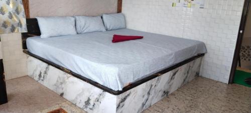 a bed with a red pillow on top of it at AK Beach House in Velankanni