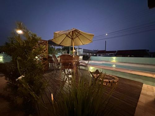 a patio with an umbrella and chairs next to a pool at 01 - Casa Praia da Pinheira in Palhoça