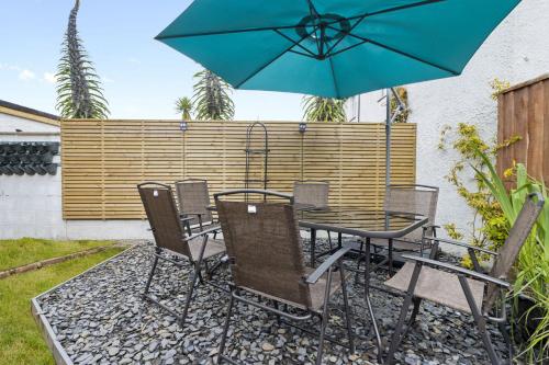 a table and chairs with a blue umbrella at Seaway Garden, Beachside Maisonette with Parking in Paignton
