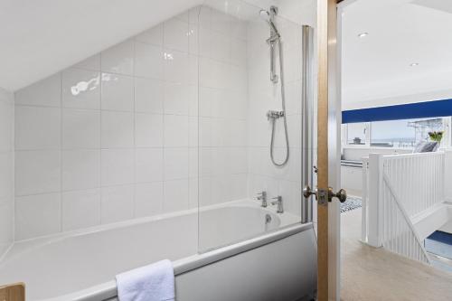 a white bathroom with a tub and a shower at Seaway Garden, Beachside Maisonette with Parking in Paignton