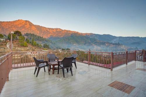 a patio with chairs and a table on a balcony at Nature's Vibe Stays Mukteshwar - A 4BHK Plum Orchard Villa in Mukteswar