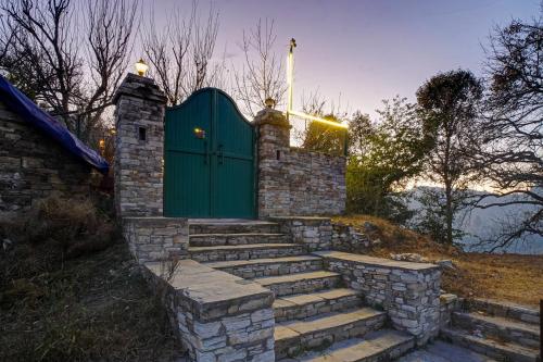 a set of stairs leading up to a green door at Nature's Vibe Stays Mukteshwar - A 4BHK Plum Orchard Villa in Mukteswar