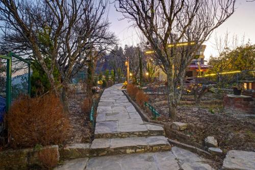 a stone path in a park with trees at Nature's Vibe Stays Mukteshwar - A 4BHK Plum Orchard Villa in Mukteswar