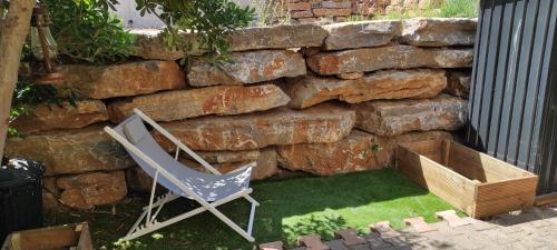une chaise assise devant un mur en pierre dans l'établissement Appartement T2 avec jardin, à Saint-Mandrier-sur-Mer