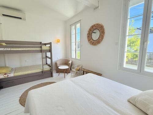 - une chambre blanche avec des lits superposés et une chaise dans l'établissement Villa Joséphine Plage de Boyard, à Saint-Georges-dʼOléron