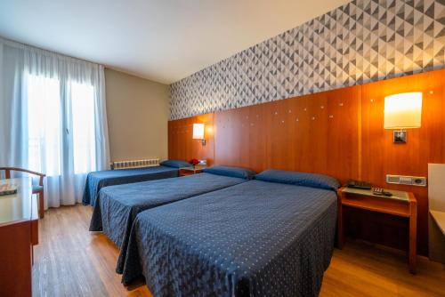 a hotel room with two beds and a window at Hotel J. Balmes Vic in Vic