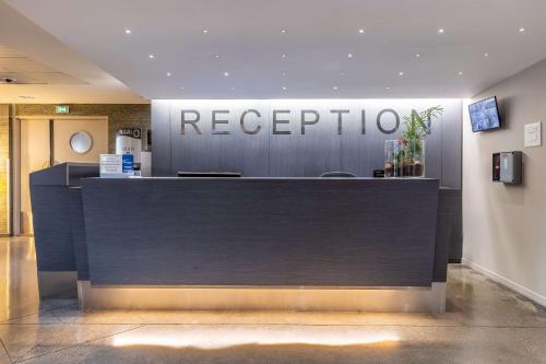 a reception desk in a building with a sign at Best Western Plus Hôtel Gergovie in Pérignat-lès-Sarliève