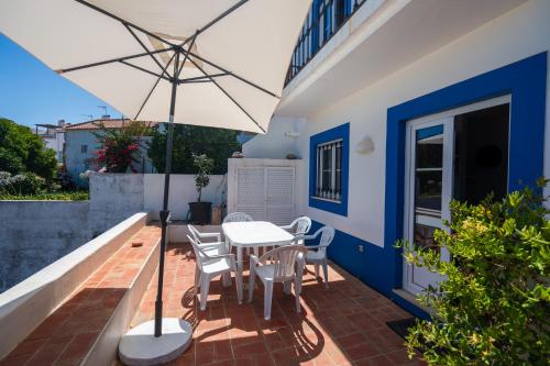 a patio with a table and chairs and an umbrella at Casa da Alba in Alentejo in Melides