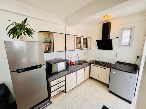 a kitchen with a refrigerator and a sink at Fibonacci Beachfront Apartment in Flic-en-Flac