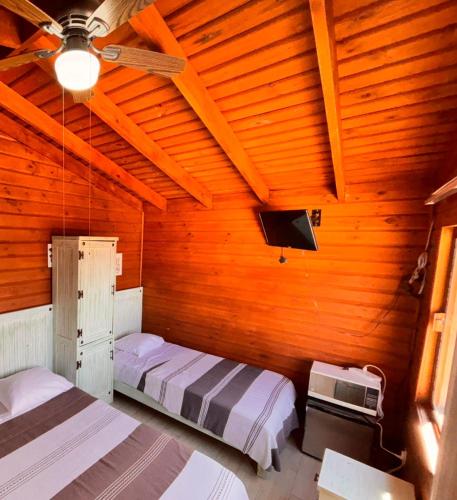a bedroom with two beds and a tv in it at Cabañas Tr'eje in Valle de Bravo