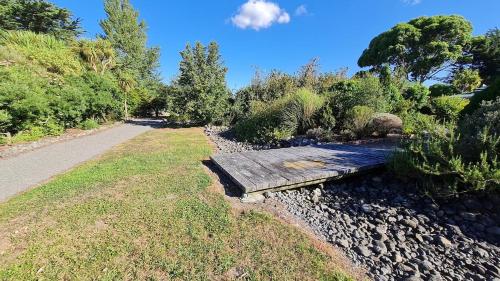 a wooden bench sitting on the side of a path at Bidwills Gem in Greytown