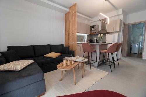 a living room with a black couch and a kitchen at Minimal Trikala Escape in Tríkala