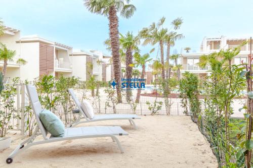 a pair of chairs on the beach with palm trees at Wave Island in Lido di Jesolo
