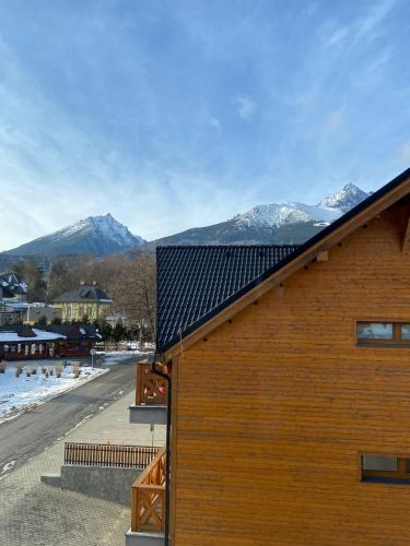 a wooden building with snow covered mountains in the background at Lomnica Lodge in Vysoké Tatry