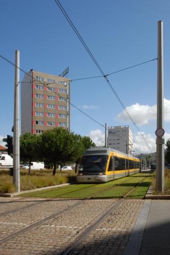 a train traveling down the tracks in a city at Hotel Amadeos - Matosinhos - Porto in Matosinhos