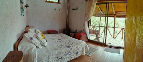 a bedroom with a bed and a large window at Refugio de Montaña Kultrun Mawida, Cabaña Mirador WIFI in Curacautín