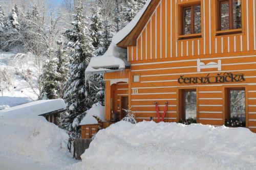 a ski lodge with a pile of snow in front of it at Apartmány Černá Říčka in Desná