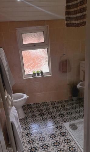 a bathroom with a toilet and a window at Seaside Apartment in Moreton