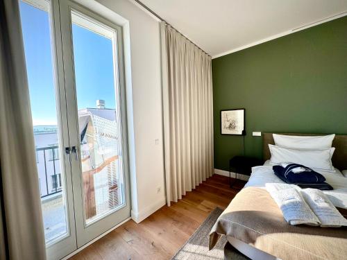 ein Schlafzimmer mit einer grünen Wand und einem großen Fenster in der Unterkunft FIRST im FIRST Sellin, Penthouse Meer & Meer mit phänomenalem Ostseeblick in Ostseebad Sellin