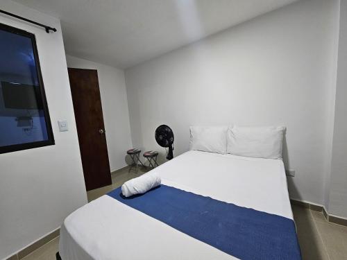 a bedroom with a white bed with a blue blanket at Andaliving Campo Valdés in Medellín