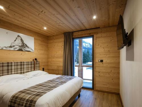 une chambre avec un lit et une grande fenêtre dans l'établissement Chalet en triplex pour 14 personnes avec Wifi, parking et terrasse - FR-1-263-546, à Valloire