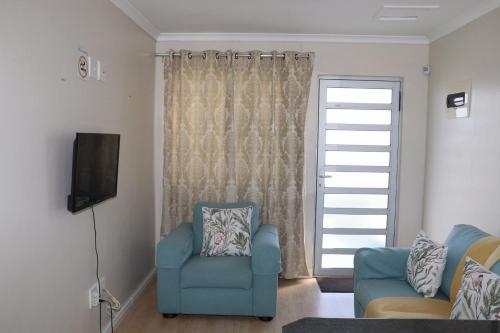 a living room with a blue chair and a television at Tygerviews on Uys in Tygerberg Hills