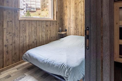 Ce lit se trouve dans une chambre en bois dotée d'une fenêtre. dans l'établissement Le BH 22, à La Bresse