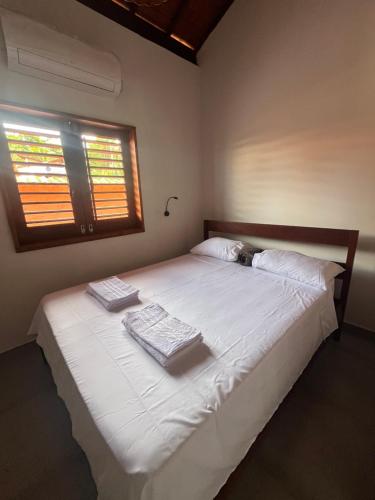 a bedroom with a large white bed with towels on it at Casa Umbuê 01 - Vista Mar in Cayru