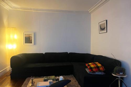 un salon avec un canapé noir dans une pièce dans l'établissement Charming spacious T2 in the 18th - Paris, à Paris
