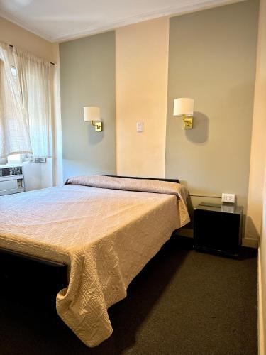 a bedroom with a large bed with two lamps on the wall at Hotel Miami in San Miguel de Tucumán