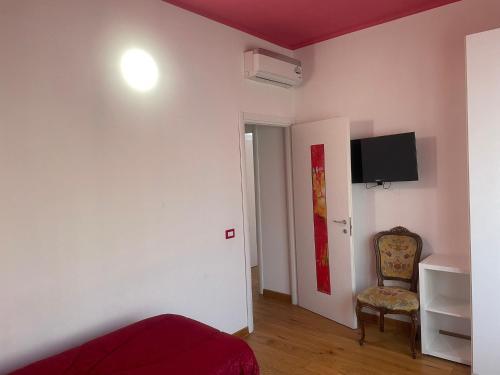 a room with a bed and a chair and a tv at Rooms Of Love in Pavia