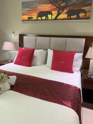 a bedroom with a large bed with red pillows at The Pillows Suite in Pretoria