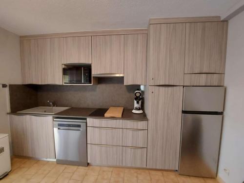 une cuisine avec des armoires en bois et un réfrigérateur en acier inoxydable dans l'établissement Confortable 2 pièces cabine, 6 pers, parking à Marseillan-Plage - FR-1-326-839, à Marseillan